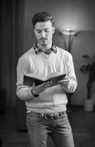 Beau jeune homme lisant le livre à la maison dans son salon — Photo