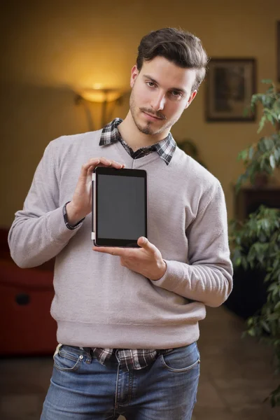 Bonito jovem em casa com tablet PC em suas mãos — Fotografia de Stock