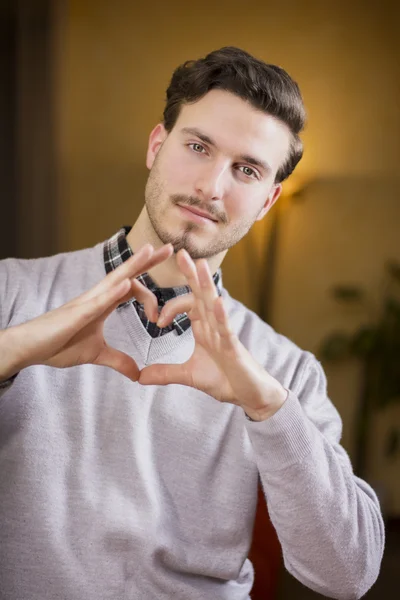 Handsome young man making heart sign with hands — Stock Photo, Image