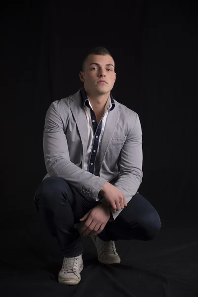 Portrait of handsome young man with shirt and jacket sitting on his heels — Stock Photo, Image