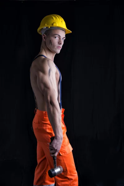 Handsome young construction worker with naked torso, hardhat and hammer — Stock Photo, Image