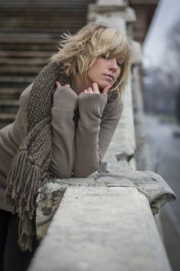 Mermer korkuluk çubuğu eğilerek, çekici, sarışın genç kadın