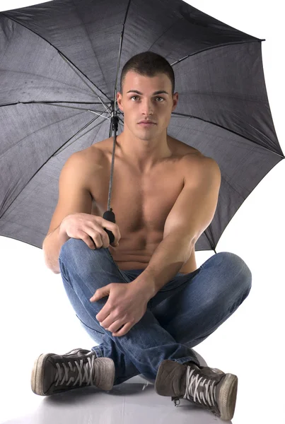Torso nudo giovane sul pavimento sotto l'ombrello e guardando la telecamera, — Foto Stock