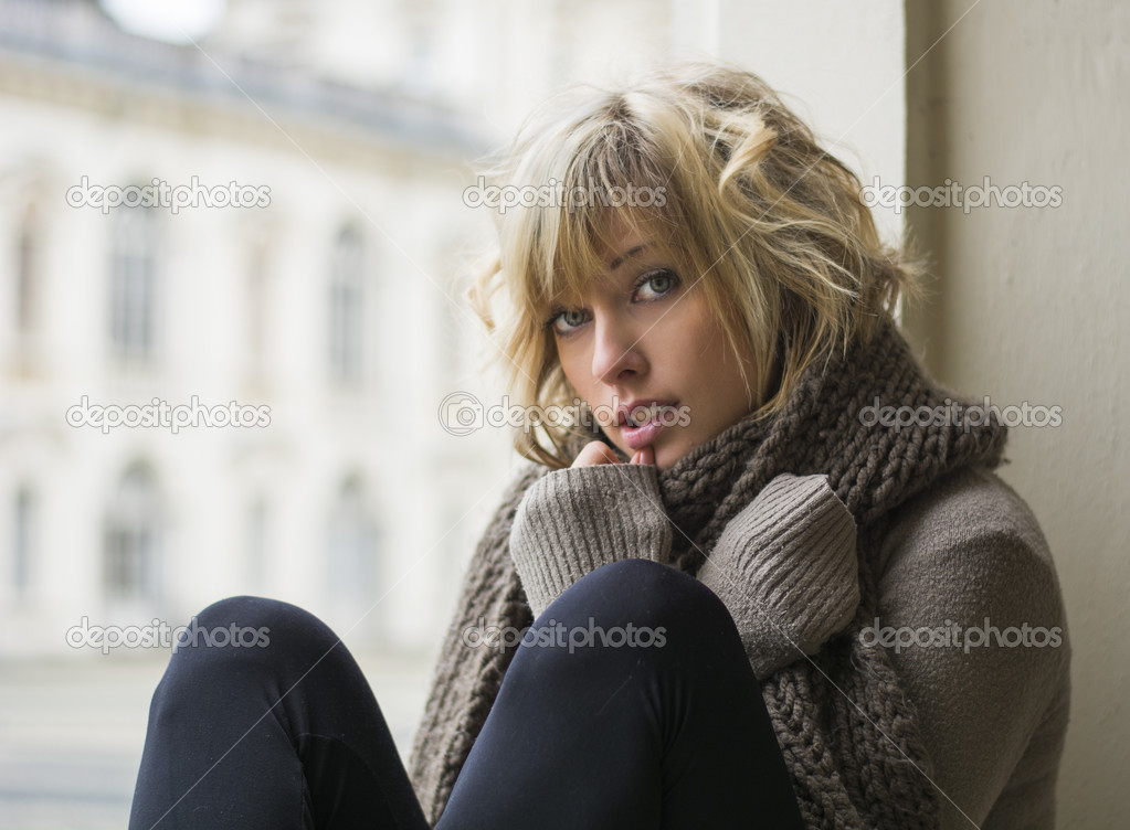 Attractive blonde young woman sitting next to window