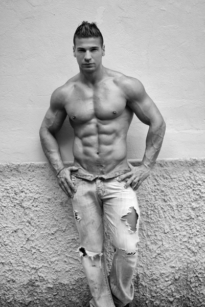 Привлекательный молодой человек без рубашки с джинсами, прислонившись к стене — стоковое фото