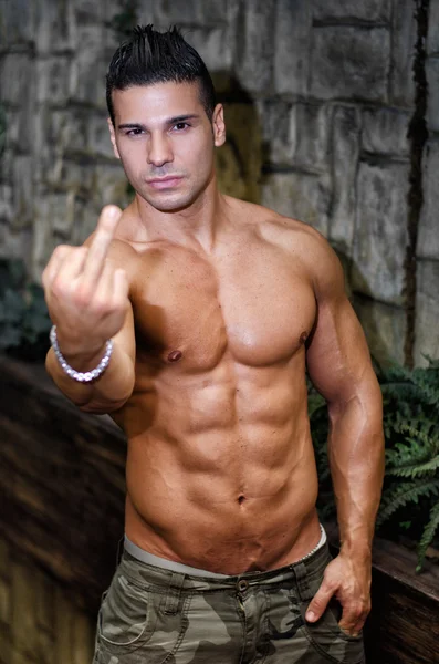 Muscular, shirtless young man doing 'screw you' sign with middle finger — Foto Stock