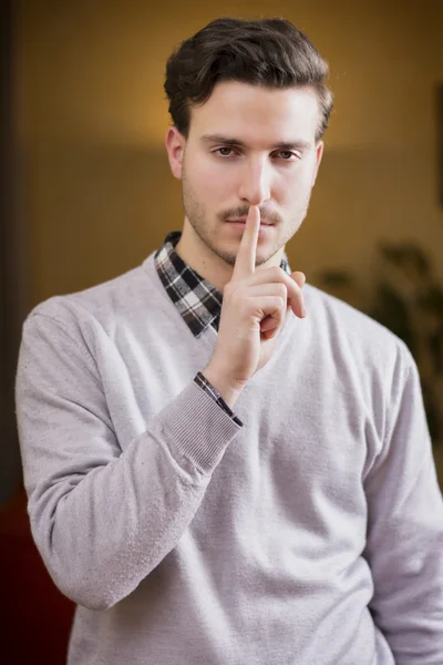 Bonito jovem fazendo Hush sinal com o dedo nos lábios — Fotografia de Stock