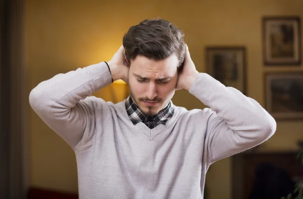 Pohledný mladý muž si zakrývá uši, příliš mnoho hluku — Stock fotografie