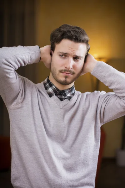 Pohledný mladý muž si zakrývá uši, příliš mnoho hluku — Stock fotografie
