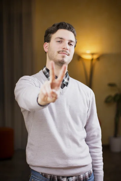 Attractive young man doing peace or victory sign — Stock Photo, Image