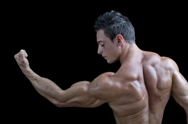 Volta de jovem fisiculturista muscular. olhando para o bíceps — Fotografia de Stock