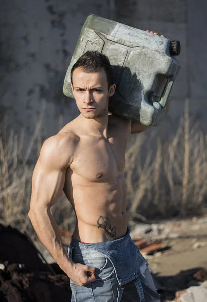 Muscular shirtless young man working. Carrying plastic canister on shoulder — Stock Photo, Image