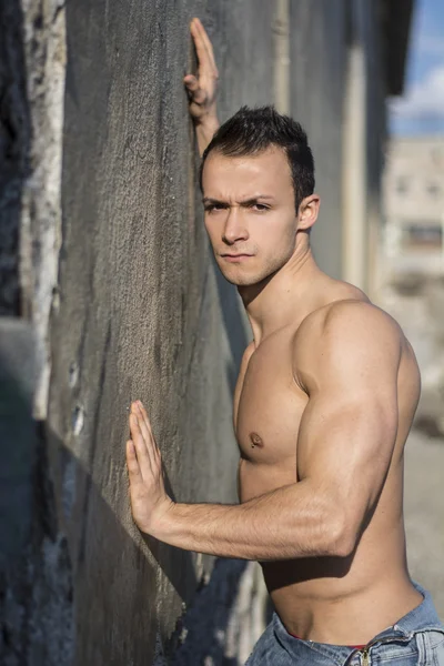 Muskulös ung man bar överkropp, lutad mot betongvägg — Stockfoto