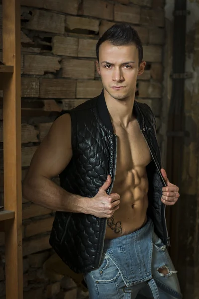 Muscoloso torso nudo giovane con jeans e giacca senza maniche — Foto Stock