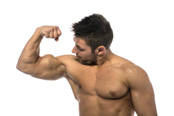 Muscular jovem sem camisa flexionando e olhando para bíceps — Fotografia de Stock