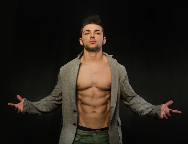 Jovem confiante e atraente, com casaco aberto no torso muscular — Fotografia de Stock