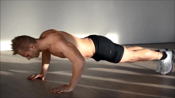 Guapo joven en el gimnasio haciendo flexiones en el suelo — Vídeo de stock