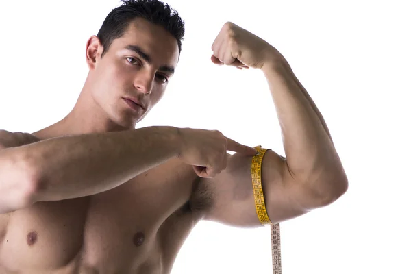 Muscular shirtless young man measuring arm with tape measure — Stock Photo, Image