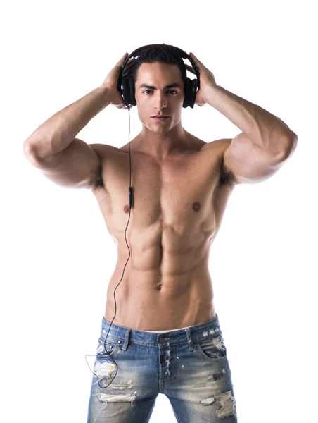 Muskulös man står, lyssna på musik i hörlurar — Stockfoto