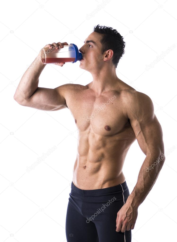 Muscular shirtless male bodybuilder drinking protein shake from blender