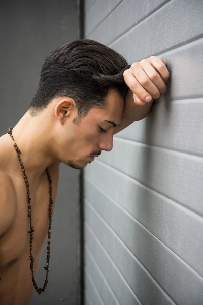Verdrietig, depressief, ongelukkige jonge man tegen muur — Stockfoto