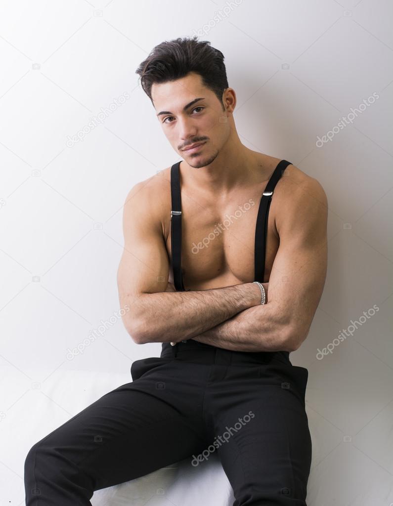 Shirtless athletic young man with suspenders and black pants