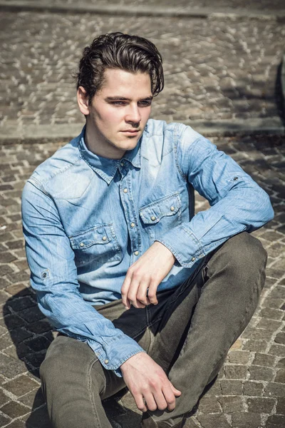Jovem atraente, sentado na calçada, ao ar livre — Fotografia de Stock