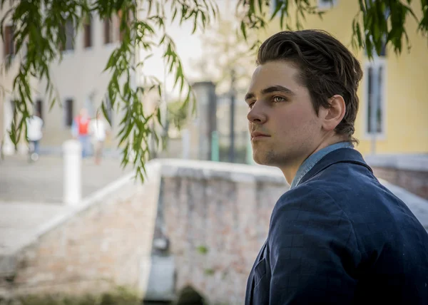 Handsome young man under a tree in town setting — Stock Photo, Image