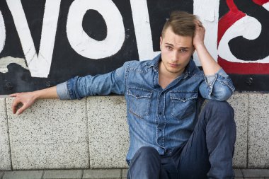Renkli grafiti duvara oturan sarışın yakışıklı genç