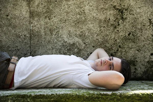Knappe jongeman liggen op stenen blokken — Stockfoto