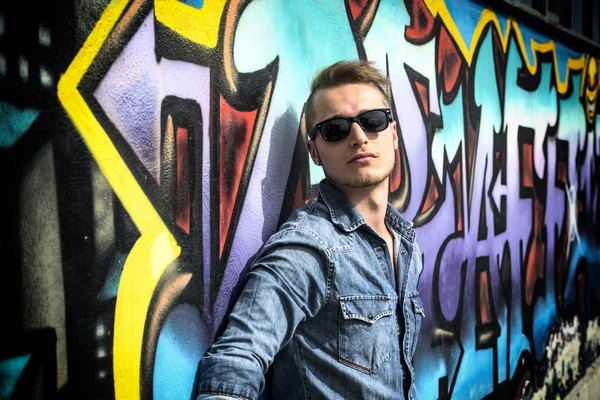 Attraktiv ung blond man mot färgglad graffiti vägg — Stockfoto