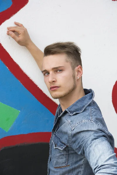 Attraktiv ung blond man mot färgglad graffiti vägg — Stockfoto