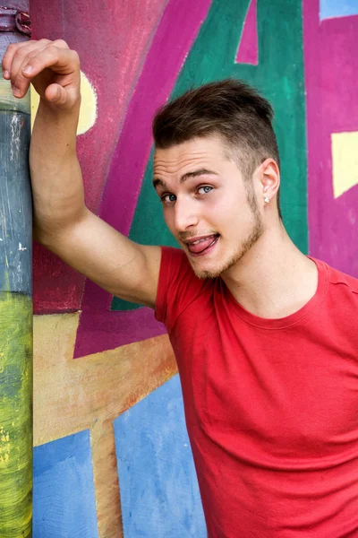 Handsome blond young man against colorful graffiti wall — Stock Photo, Image