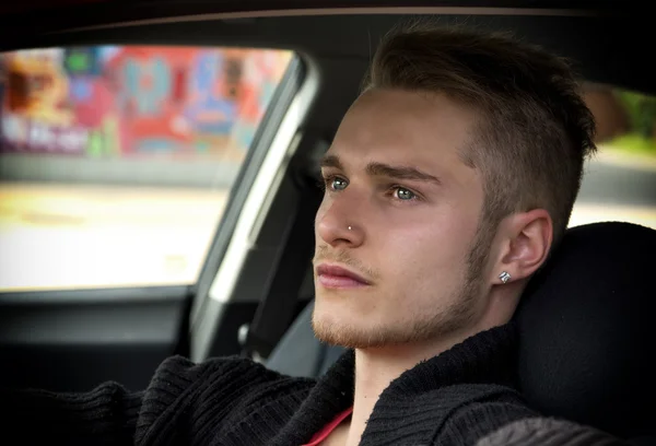 Aantrekkelijke jonge blonde man zit in zijn auto — Stockfoto