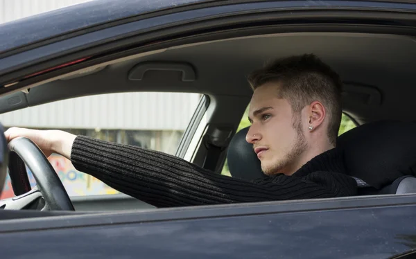 Aantrekkelijke jonge blonde man zit in zijn auto — Stockfoto