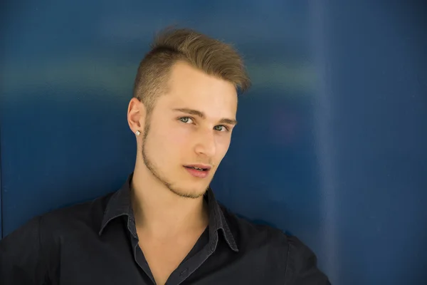 Aantrekkelijke jonge blonde man op blauwe muur — Stockfoto