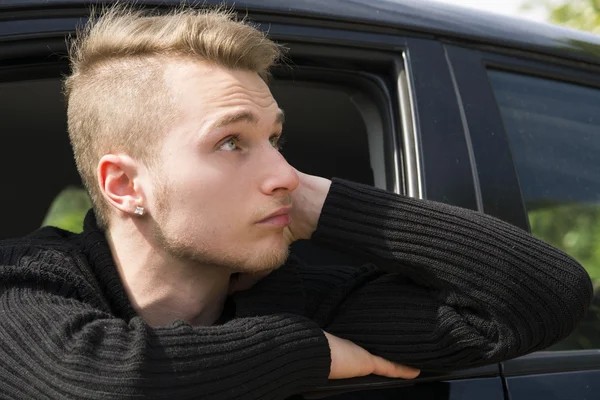 Красивый белокурый молодой человек, сидя в своей машине — стоковое фото