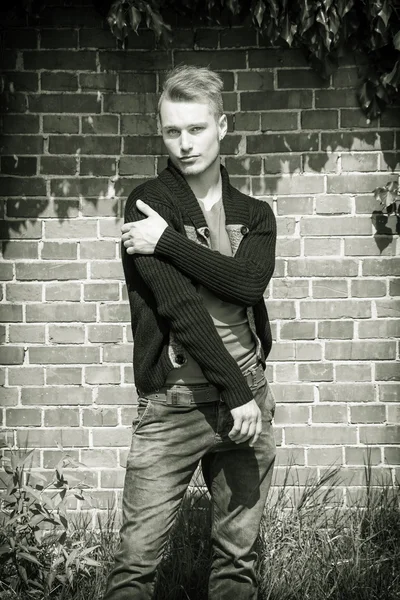 Handsome blond young man outside in front of brick wall — Stock Photo, Image