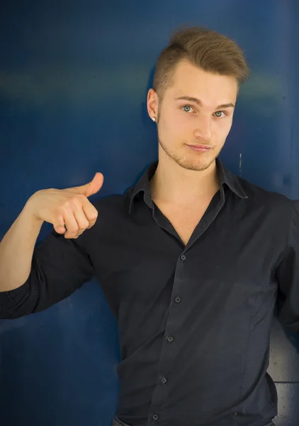 Ελκυστική ξανθιά, μπλε eyed νεαρό άνδρα χαμογελώντας και κάνει αντίχειρα σημάδι — Φωτογραφία Αρχείου