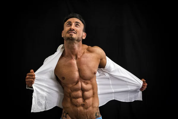 Male bodybuilder taking off his shirt revealing muscular torso — Stock Photo, Image