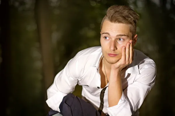 Seriöser junger Mann draußen im Park bei Nacht — Stockfoto