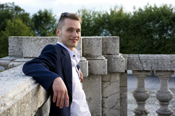 Schöne blonde junge Mann auf Marmor Geländer — Stockfoto