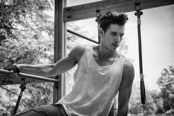 Joven guapo haciendo ejercicio en el gimnasio al aire libre en el parque — Foto de Stock