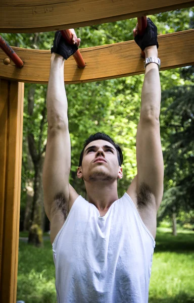 Park açık spor salonunda egzersiz yakışıklı genç — Stok fotoğraf