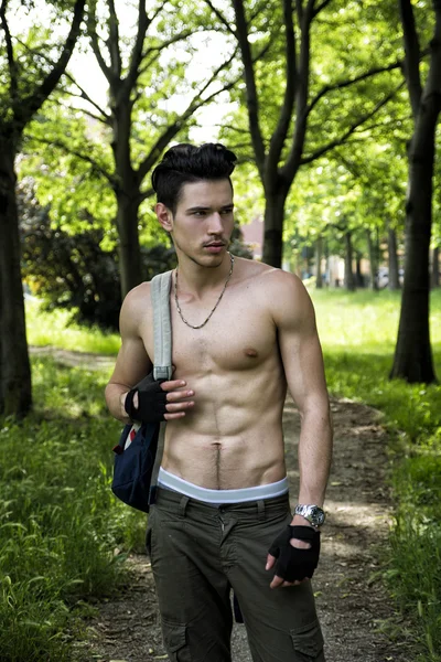 Young man shirtless outdoors hiking with backpack on shoulder — Stock Photo, Image