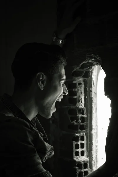 Jeune homme intérieur crier par trou dans le mur — Photo