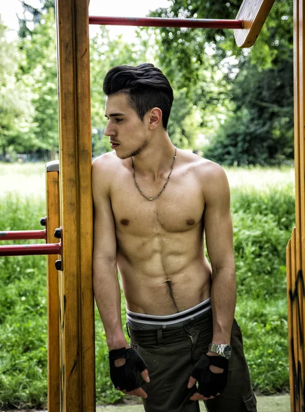 Handsome shirtless young man exercising in outdoor gym in park — Stock Photo, Image