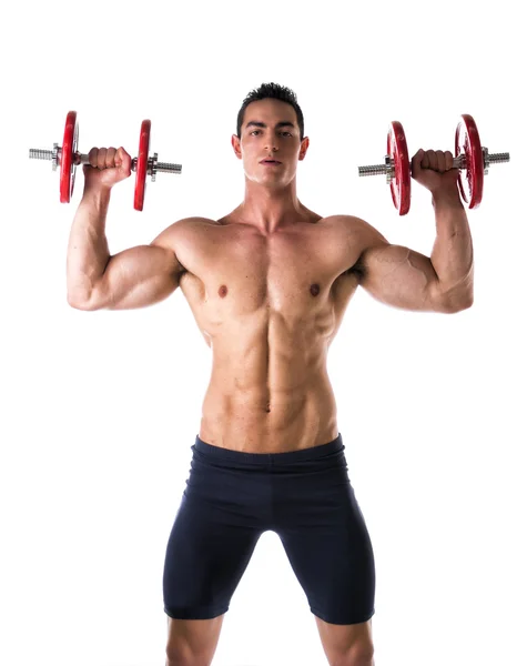 Muscular shirtless young man exercising shoulders with dumbbells — Stock Photo, Image