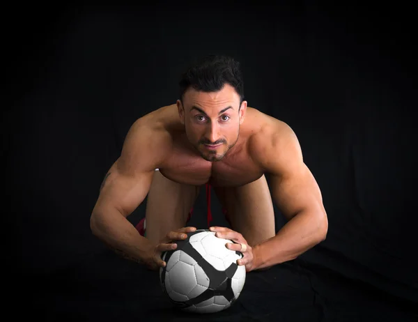 Hombre musculoso sin camisa en el piso con balón de fútbol — Foto de Stock