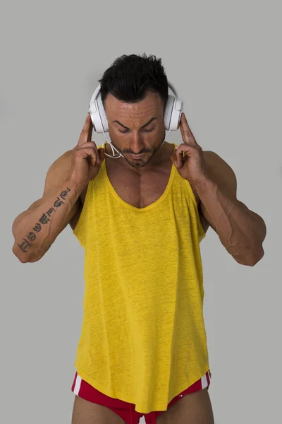 Muscular man standing, listening to music on headphones — Stock Photo, Image